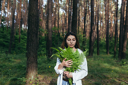 在树林里的女人拥抱着一束野生的花束 一个年轻的积极分子保护森林季节头发眼睛摄影植物生态皮肤女性公园化妆品图片