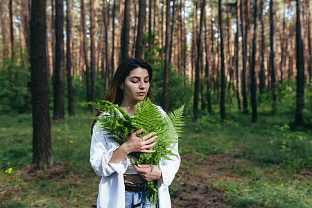 在树林里的女人拥抱着一束野生的花束 一个年轻的积极分子保护森林摄影护理植物蕨类叶子头发女孩女性青少年眼睛图片