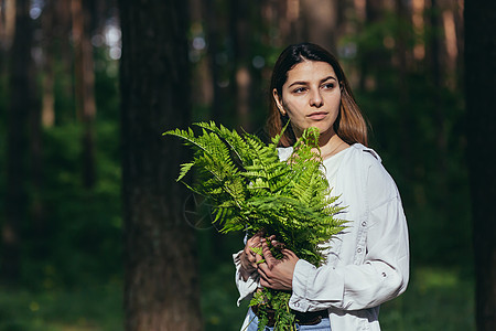 在树林里的女人拥抱着一束野生的花束 一个年轻的积极分子保护森林女孩头发植物生态化妆品木头摄影蕨类女性皮肤图片