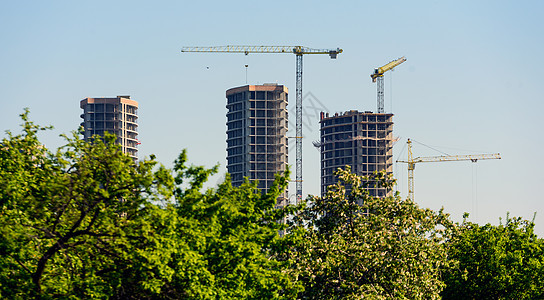 在建造多层建筑 树木 公园的背景下 绿地面积是一片绿色的建筑物天空脚手架房地产高楼建筑摩天大楼建筑学起重机住宅城市图片