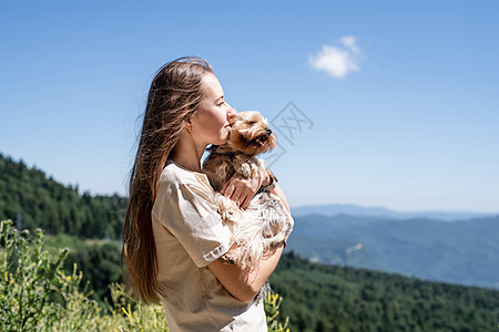 在山上徒步旅行的年轻女子 带着小狗小狗 小黄鼠狼乐趣犬类女孩头发朋友幸福公园动物猎犬友谊图片