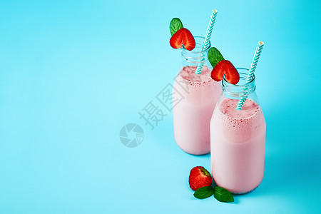 蓝底有浆果的玻璃罐中草莓冰沙或奶昔 健康暑期饮料图片