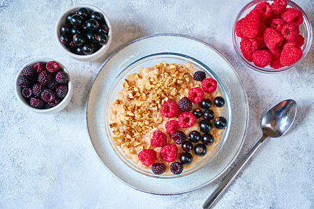 在玻璃碗里用不同的浆果和粉碎的坚果做燕麦 健康平衡的食物图片