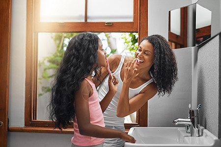 我看看 一个有魅力的年轻女人和她的女儿 在家里洗手间里刷牙时图片