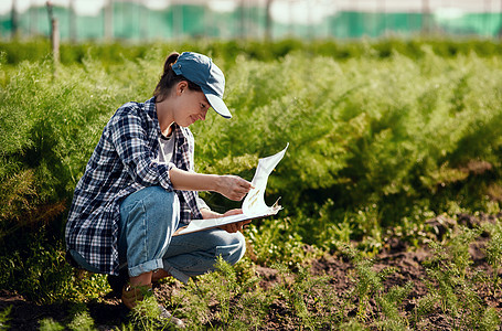 年轻的女农民在她的农田工作时准备收获 确保有机土壤在外面新鲜且可持续 快乐的工人阅读她的剪贴板笔记以检查农田图片