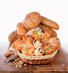 面制品 白色背景中不同类型面包和甜面包的柳条篮图片