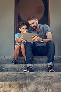 从爸爸那里可以学到很多东西 父亲和儿子在家里前台用数字平板电脑一起学习 (笑声)图片