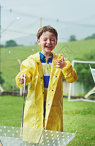 雨不打扰他 一个开朗的小男孩白天在外面被雨淋湿时撑着伞站着图片