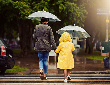 在路上 我们冒雨前行 后视镜头 一个面目全非的小男孩和他的母亲手牵着手在外面的雨中行走图片