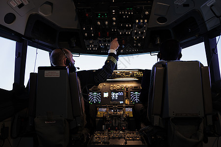 男机长在飞机驾驶舱按仪表板按钮图片