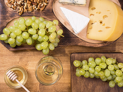 法国葡萄木制桌上各种奶酪旁边新鲜葡萄的顶端景色背景