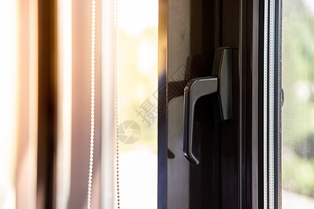 棕色金属塑料窗上的窗口手柄 阳光通过它照亮图片