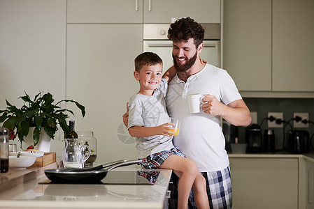 和爸爸一起开始新的一天 一个可爱的小男孩和他的父亲在家里一起喝咖啡和果汁图片