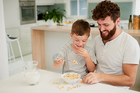 一个可爱的小男孩 和他父亲在家一起吃早饭 他家的早餐很甜美啊图片