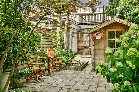 带有坐地的Neat天台花园后院家具石头桌子植物院子庭院铺路扶手椅背景图片