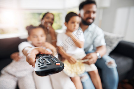 与家人一起在客厅看电视的遥控器特写 父母和孩子在沙发上放松 在家里的休息室里看电影 连续剧或卡通片 同时保持亲密图片