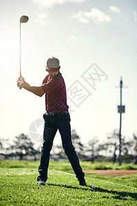 向后拉并摆动 一位专注的年轻男性高尔夫球手即将在球场外挥杆并用他的高尔夫球杆击球图片