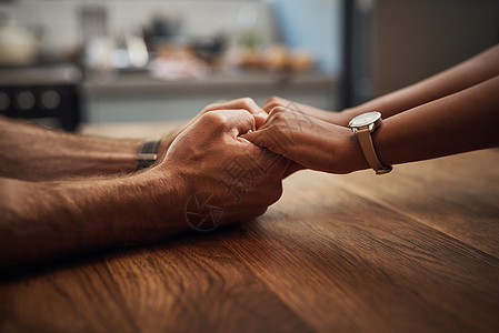 一对夫妇在家中的木制桌子上手牵手支持 悲伤和愈合 一位爱心伴侣因癌症而悲痛地关紧 并在家里表达同情之情;他图片