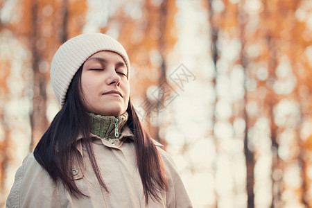 女孩在公园散步时享受清秋新鲜空气女性黑发阳光绿地照片季节眼睛帽子木头金子图片