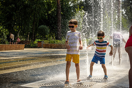 男孩在喷泉中玩耍 在炎热的夏日玩城市喷泉的孩子 快乐的孩子们在喷泉中玩耍 夏天的天气 积极的休闲 生活方式和假期运动太阳流动乐趣图片