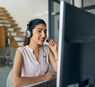 一位年轻女性在呼叫中心用电脑工作 她随时可以接听任何电话图片