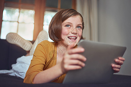 一个可爱的小姑娘 在家里的地板上用数码平板电脑玩弄了这个游戏 她是个可爱的女孩图片
