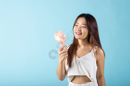 亚洲美貌年轻女性 将粉红色手提式电子迷你风扇贴近脸部运动技术女孩螺旋桨空气塑料蓝色机器冷却器女士图片