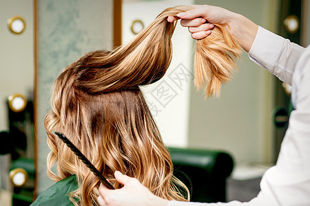 发型师握着一束头发梳子手指成人梳妆台理发造型客户发型沙龙女性图片