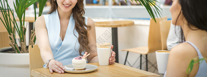 两名年轻妇女喝咖啡社交闲暇桌子咖啡购物中心享受闺蜜成人午餐八卦图片