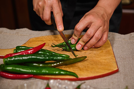 厨师的手用菜刀在砧板上切红辣椒和绿辣椒 切食物 辣味料图片