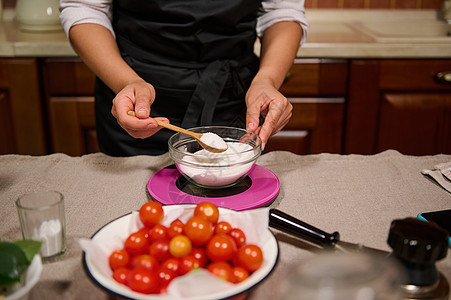 详情 家庭主妇的手握着木茶匙 在煮番茄和罐头时称厨房糖量重图片