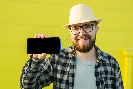 快乐的家伙拿着手机 有黑色的复制空间和微笑 人类情感面部表情以及广告和文字的地方 笑声男人工具技术互联网展示男性电话帽子触摸屏商背景图片