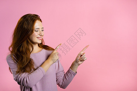 笑得开心的女士在粉红色背景上展示和展示一些孤立的东西 女孩的肖像 她用手臂指向左侧并带有复制空间力量广告牌成人生意人领导黑发商务图片