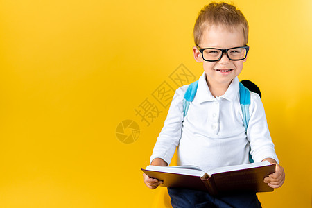 戴着大眼镜的横幅滑稽学龄前儿童男孩在黄色背景复制空间上读书 快乐微笑的孩子回到学校 幼儿园 成功 动机 赢家 天才 超级英雄概念图片