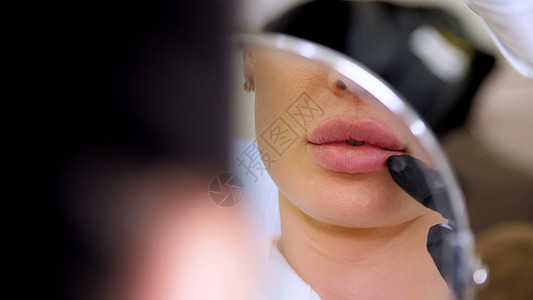 医疗办公室 美丽的女人照镜子 医生在将透明质酸注射到嘴唇后探查患者的嘴唇 矫正嘴唇的形状药物学校医疗柜女士整容药品诊所麻醉不育美图片