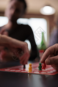 近距离拍下玩家手在坐在桌上的游戏上移动塑料雕像图片