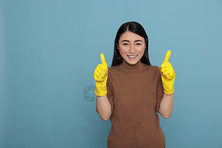 快乐乐观的年轻女性亚洲人大拇指举起并戴黄色手套图片