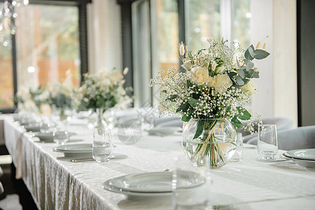 餐厅的婚礼接待台装饰了白蜡烛和鲜花 并配有白色蜡烛和鲜花刀具庆典花束奢华桌子玻璃桌布宴会餐饮餐巾图片