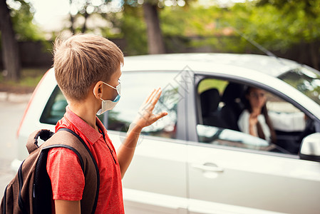 上学前 戴着医用口罩的小男孩在车里向妈妈挥手告别图片
