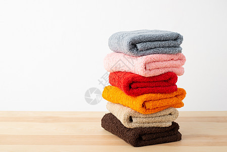 在白色背景的木制桌布上为洗手间铺装新鲜彩色毛巾图片