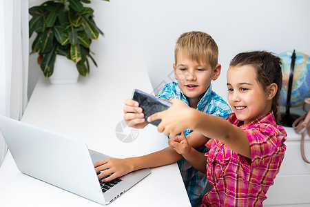 在家玩笔记本电脑的儿童男生桌子孩子们女孩娱乐沙发互联网客厅工作长椅背景图片