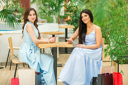 两名妇女坐在桌子上技术假期电话快乐咖啡店黑发闲暇微笑女孩咖啡图片