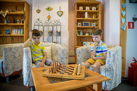 下棋时生动的情绪 酒店大堂内的两名年轻棋手 比赛棋竞争概念孩子们兄弟游戏数字专注桌子公园男性乐趣童年图片