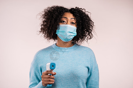 戴保护面罩的非洲妇女将电子非接触温度计引导到相机镜头中 测量温度等值症状保健流感发烧摄氏度乐器疾病女性女孩药品图片