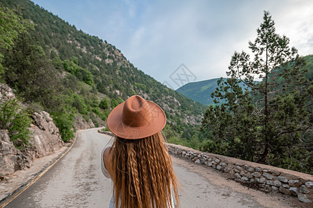 穿着棕帽子和白衣服的女性旅行者 看着令人惊叹的山峰和森林 漫游概念 大气史诗时刻游客探索冒险远足树木晴天旅行山脉背包荒野图片