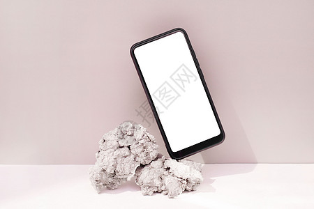 在粉红背景上的天然石上平衡的模拟模版智能手机 带空白屏幕模板的电话背景图片