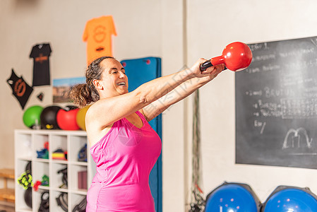 肌肉锻炼女子在健身房做水铃摇摆运动背景