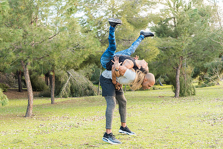 男人运动情侣在公园里做后背起接运动的健身夫妇活动行动动机耐力背靠背肌肉运动员两个人伙伴女士背景