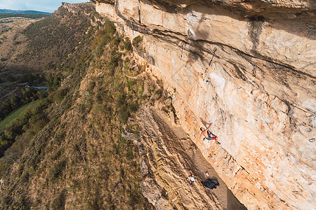 空中观视着一个攀岩者 爬上岩石层 人们从地上观看绳索场景活动运动攀岩锻炼手臂运动员风险成功图片