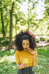 漂亮的阿弗罗女人在花园里聊天 非常惊讶技术惊喜女士拉丁黄色女孩消息电话情感女性图片